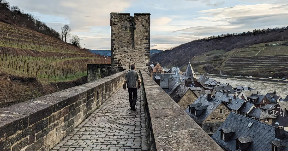Walkable section of the medieval town wall above slate roofs and vineyards